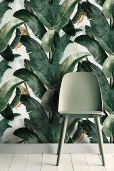 a white chair sitting in front of a wall with green leaves on it's sides