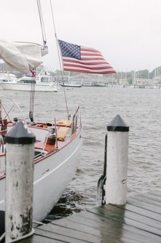 a sailboat docked at a pier with an american flag in the background