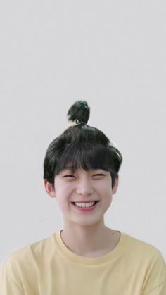 a young woman smiling and wearing a yellow shirt with a bird on top of her head