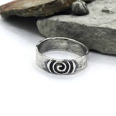 Description: SImple ring with softly textured band, center piece is a life spiral with a raised design. Available to ship Size: 4-14 I can size in whole, half or quarter sizes because we don't all fit perfectly in the whole sizes. Depending on the ring design, the design can change depending on the size. Made to order pieces - design will vary slightly from the photo, as each ring is handcrafted just for you! Specifications: Materials: Sterling silver Approximately width 6.25 mm Jewelry by Caria Negative Space Ring, Hand Forged Spiral Ring As Gift, Hand Forged Spiral Ring For Gift, Handmade Spiral Rings For Anniversary, Hand Forged Spiral Rings For Gifts, Hand Forged Spiral Ring, Handmade Spiral Anniversary Rings, Cool Rings Unique, 80s Rings