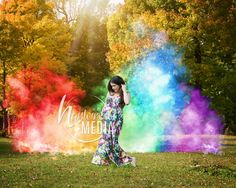 a woman standing in the grass with colored powder on her face and hands behind her head