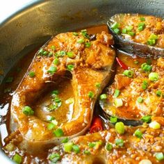 some food is cooking in a pan with green onions and sauce on the side,