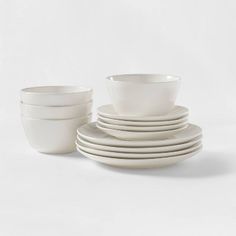 a stack of white dishes sitting on top of each other in front of a white background