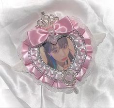 a pink and silver heart shaped brooch with a photo on it's side