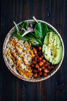 a bowl filled with rice, beans and avocado on top of a wooden table