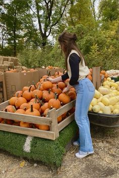 a woman standing next to a pile of pumpkins