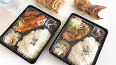 two plastic trays filled with rice, meat and veggies next to bottled water