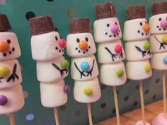 marshmallow snowmen are lined up on sticks