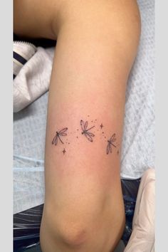 a woman's leg with three dragonflies tattoo on her left arm and two stars in the middle