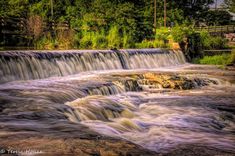 the water is flowing down the rocks in front of the waterfall and trees on the other side