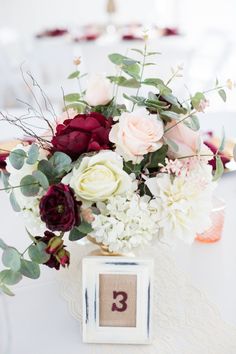 a vase filled with flowers on top of a table next to a number three sign