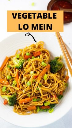 a white bowl filled with noodles and veggies next to chopsticks on a table