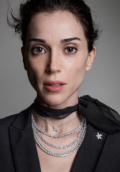 a woman wearing a black jacket and silver necklace with an embellished cross on the collar