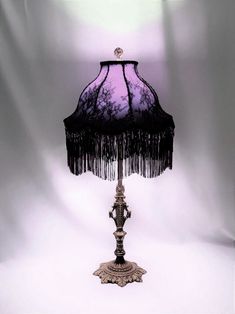 a purple lamp with tassels on it sitting in front of a white background