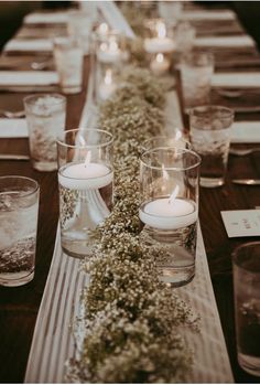 a long table is set with candles and flowers in glass vases on top of it