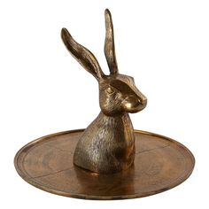 a brass colored rabbit statue sitting on top of a wooden tray with a white background