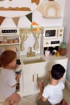 two children are playing in a toy kitchen