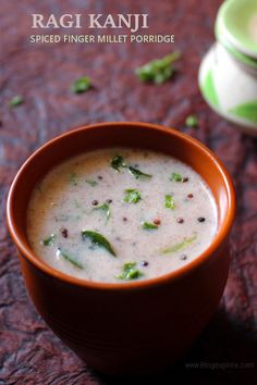 a bowl of soup is sitting on a table with another bowl in the background and an advertisement for ragi kanji spiced finger millet porridge