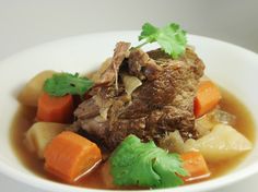 a white bowl filled with meat and vegetables