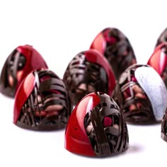 several chocolates in the shape of hearts on a white surface with red and black decorations