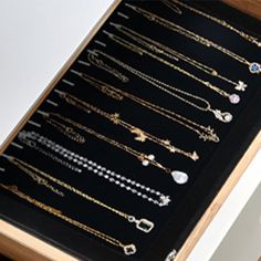 there are many different types of jewelry in this wooden display case on the counter top