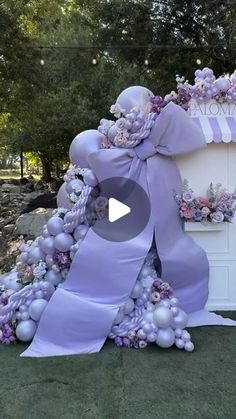 a purple and white wedding arch is decorated with flowers, pearls, and ribbons that are tied to it