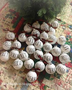 christmas ornaments with words on them sitting on a quilted tablecloth next to a tree