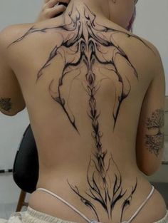 the back of a woman's body with tattoos on it