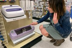 a woman kneeling down next to a machine in a store