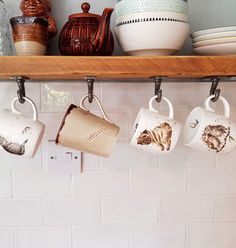 coffee mugs are hanging on the shelf above the kitchen sink