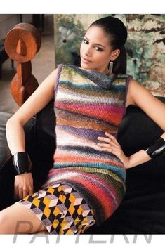 a woman sitting on top of a black couch wearing a multicolored knitted dress