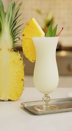 a pineapple sitting next to a drink in a tall glass on a counter top