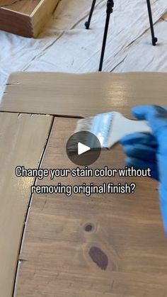 a person in blue gloves is using a tool to remove stains from wood flooring