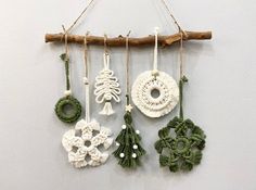 an assortment of crocheted ornaments hanging from a branch on a white wall,