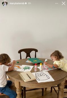 two young children sitting at a table drawing