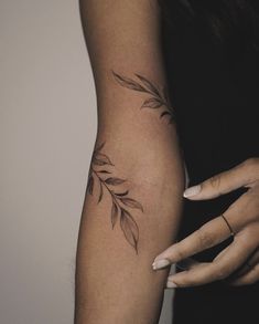 a woman's arm with leaves on it and her hand holding the other arm