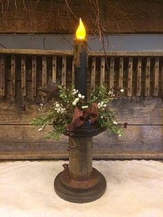 a candle is lit on top of a vase with flowers and greenery in it