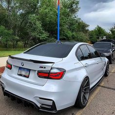 the rear end of a silver car parked in a parking lot next to other cars