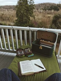 an open suitcase sitting on top of a green blanket next to a notebook and pen