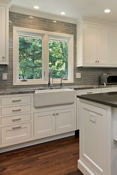 a kitchen with white cabinets and black counter tops, along with an island in the middle