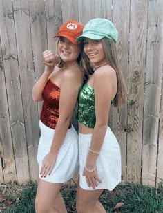 two young women standing next to each other in front of a wooden fence wearing matching hats