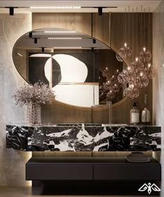 an elegant bathroom with marble counter tops and black cabinets, along with a round mirror above the sink