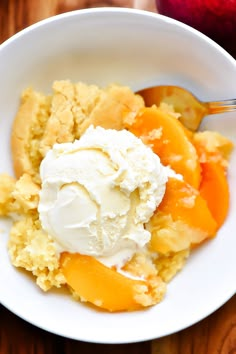 a white bowl filled with ice cream and peaches on top of a wooden table