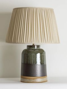 a lamp that is on top of a table next to a white wall and floor