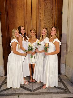 four beautiful women in white dresses posing for a photo