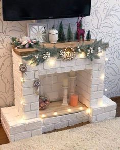 a white brick fireplace with christmas decorations and lights on it in front of a flat screen tv