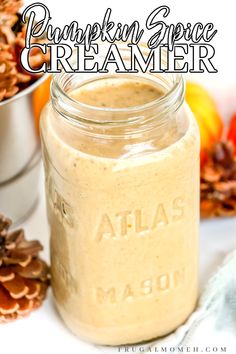 a mason jar filled with pumpkin spice creamer next to some pine cones and oranges