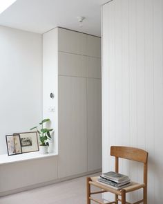 a wooden chair sitting next to a white wall