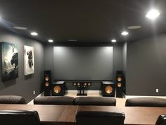 an empty room with speakers and couches in front of the projector screen on the wall