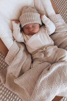 a baby is laying in a bed wearing a knitted hat